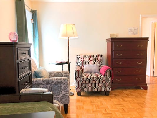 A cozy living room with patterned chairs and a standing lamp.