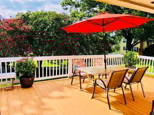 Outdoor patio with a table and chairs under a red umbrella.
