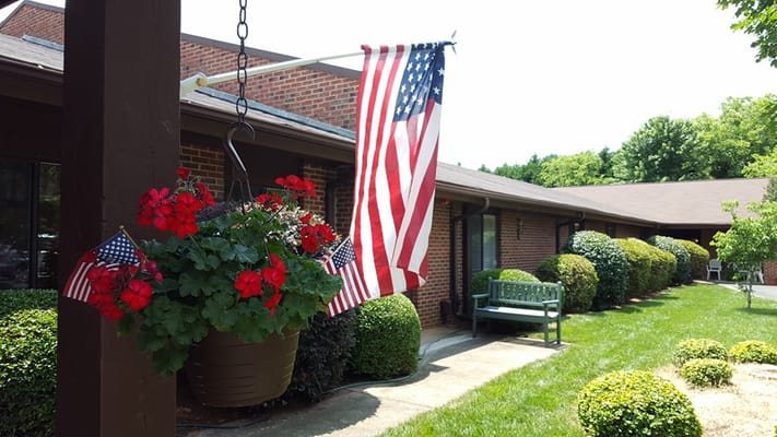 Colorful flowers and American flags outside a senior living facility