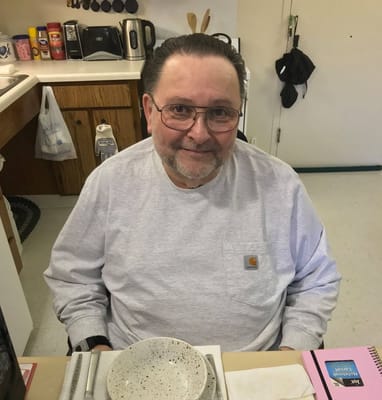 A resident smiling in a facility kitchenette