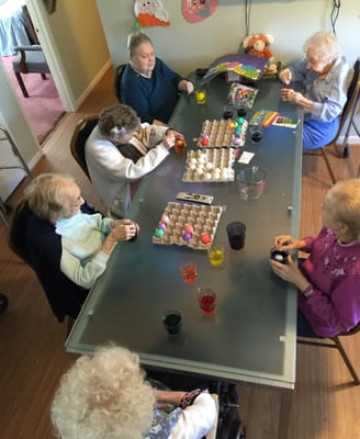Seniors participating in an egg decorating activity at a table.