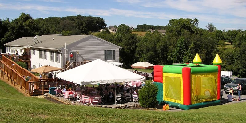 A colorful bounce house next to a tent with guests at Country Acres Assisted Living