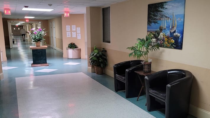 A corridor with plants and a painting in a nursing home