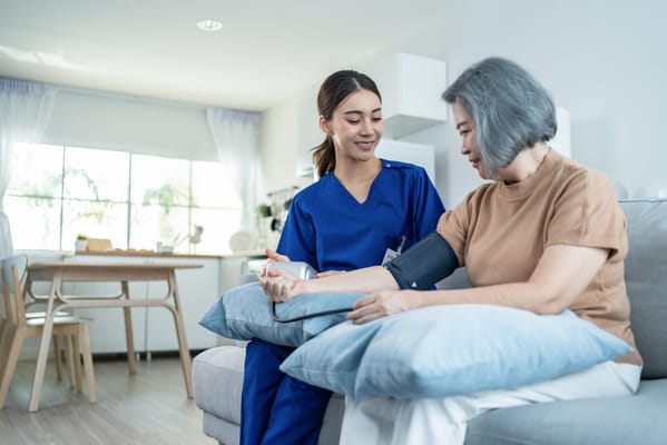 A nurse taking a resident's blood pressure in a cozy living area