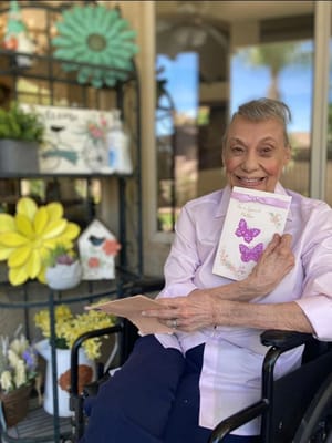 Smiling senior woman holding a card in a garden setting