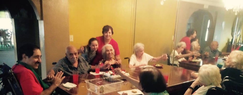 Seniors and staff gathering around a dining table in a communal area.