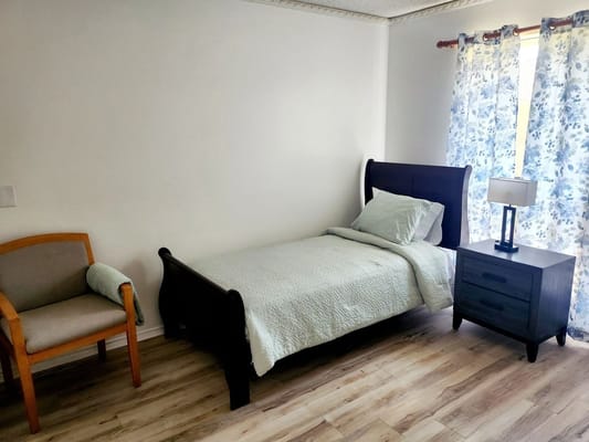A private resident room with a bed and chair