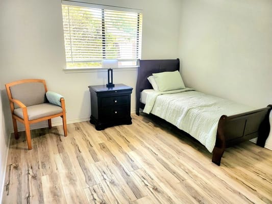 Bright and simple resident room with a bed and chair