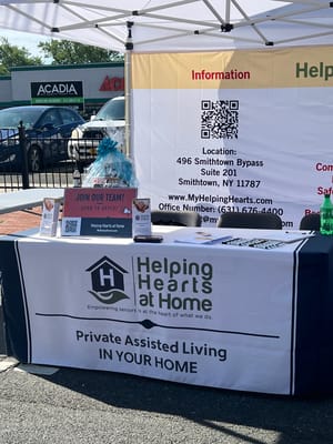 Promotional table for Helping Hearts At Home with information and recruitment materials