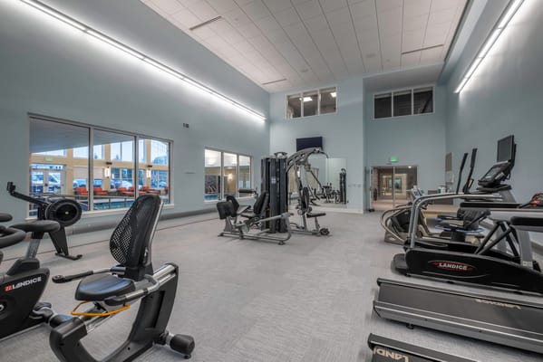 A fitness area with exercise equipment and large windows