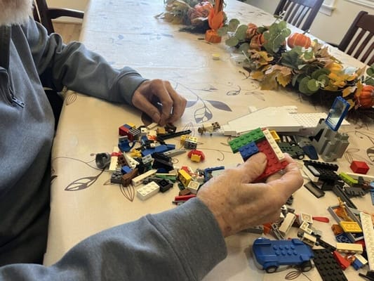 Senior resident playing with LEGO blocks at a table