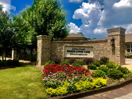 Exterior view of Johns Creek Senior Living Care with flowers and signage