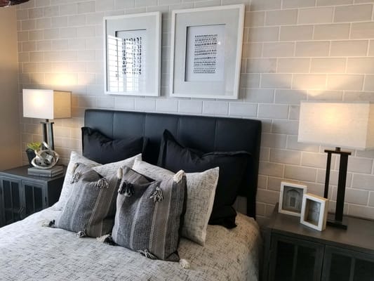 Well-decorated bedroom featuring a black headboard and assorted pillows.