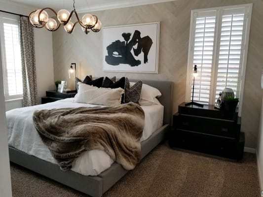Stylish bedroom with a gray bed, decorative pillows, and modern lighting.