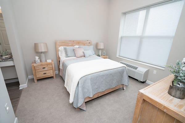 A well-furnished bedroom with a bed, bedside tables, and a window.