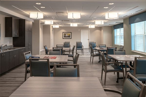 Bright common area with tables and chairs in Kingsley Senior Living facility
