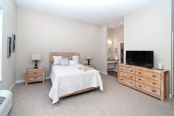 A well-furnished bedroom with a bed, bedside tables, and a television.