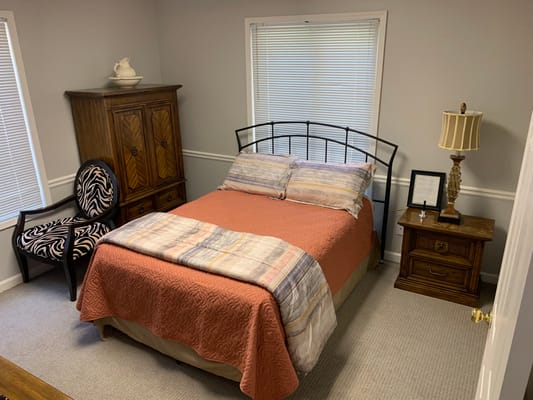 A well-furnished bedroom with a bed, nightstand, and a patterned chair.