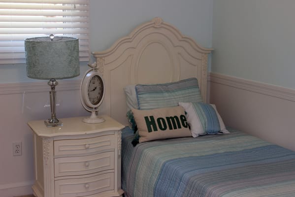 A well-decorated bedroom with a bed, pillows, lamp, and clock.