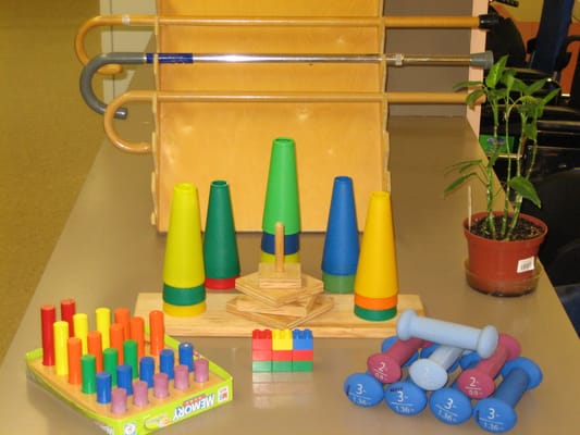Colorful activity supplies including cones, blocks, and dumbbells on a table