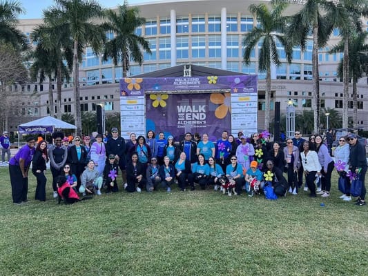 Participants gather at the Walk to End Alzheimer's event with a backdrop of the Memorial Manor facility.