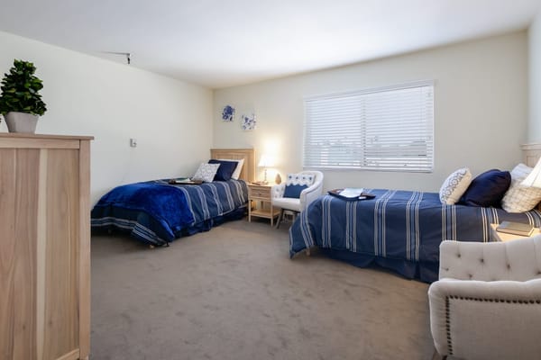 Bright and cozy bedroom with two beds and a comfortable chair