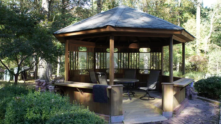 Wooden gazebo with seating in a serene garden setting