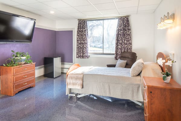 A bright resident room with a bed and amenities