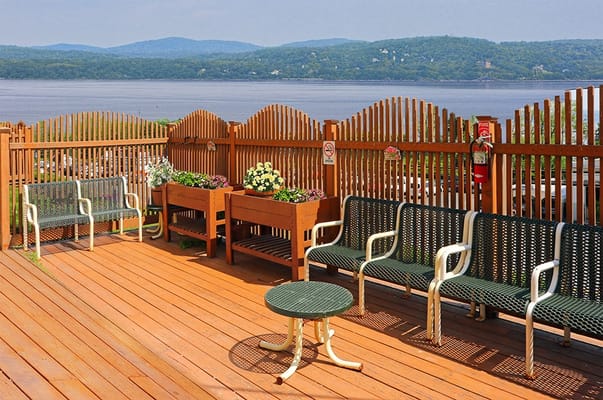 Wooden outdoor patio area with seating and flower planters overlooking the river.