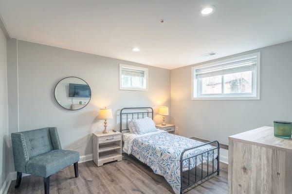 Cozy bedroom with a bed, chair, and lamp.
