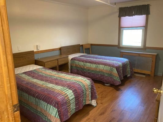Two beds in a shared bedroom with wooden furniture