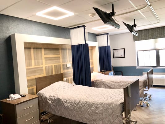 Inside view of a shared patient room with two beds and modern amenities.