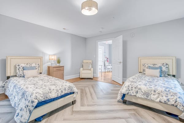 A cozy bedroom with two twin beds and a comfortable chair.