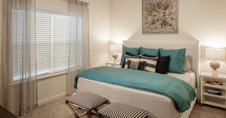Bedroom with a bed, decorative pillows, and natural light