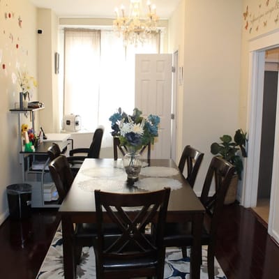 A dining area with a dark wooden table and chairs, decorated with flowers.