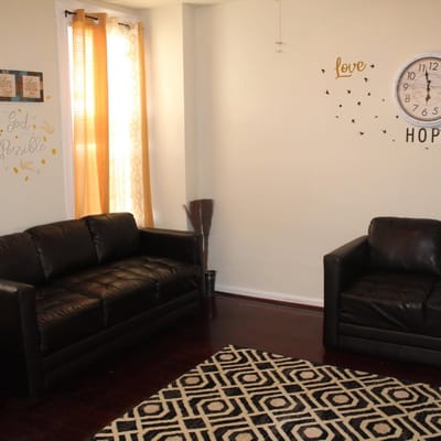 Two black leather sofas in a cozy living room with decorative wall art