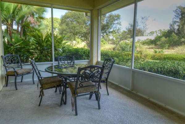 Patio furniture set on a screened porch with a view of greenery