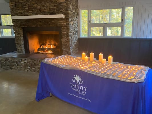 A table with candles in front of a stone fireplace