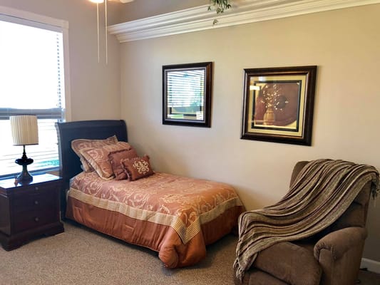 A cozy bedroom with a single bed, nightstand, and armchair