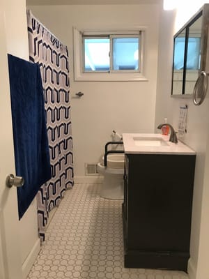 A clean and well-lit bathroom with a shower curtain and white tiled floor.