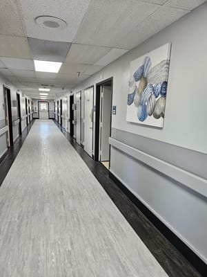 Long hallway with rooms on either side and a painting on the wall