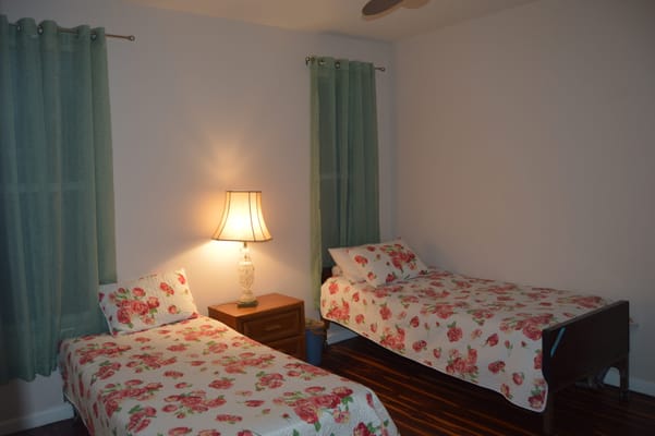 A cozy bedroom with two beds, floral bedding, and a lamp.