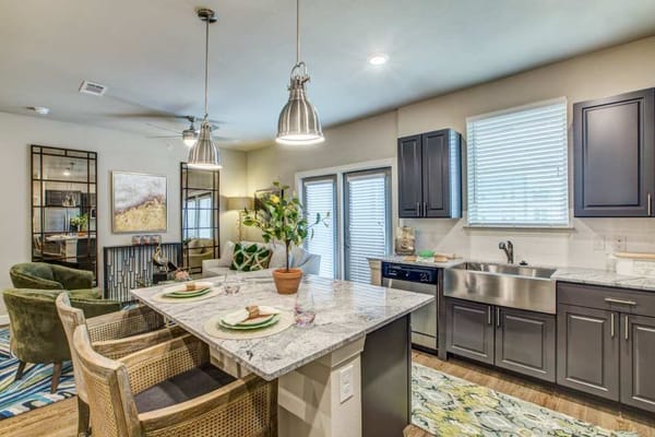Bright kitchen with dining area featuring a marble table and green chairs.