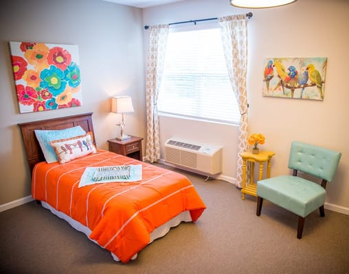 Brightly decorated bedroom with orange bedding and floral artwork