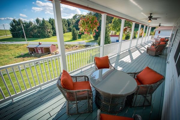Spacious veranda with wicker chairs and table overlooking greenery