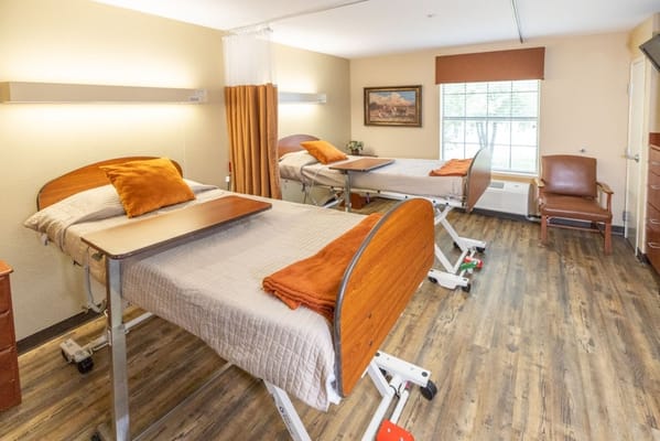 A well-furnished resident room with two beds and a chair