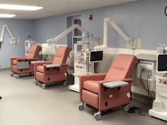A treatment room with pink reclining chairs and medical equipment.