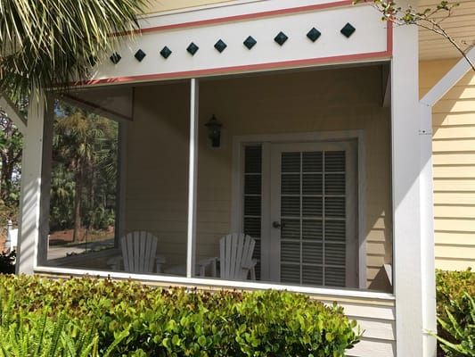 Porch seating area with white chairs and greenery