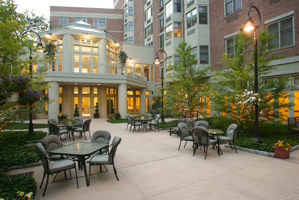 Outdoor seating area with tables and chairs surrounded by greenery.