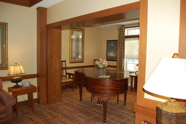 A cozy common area featuring a piano, chairs, and decorative lamps.
